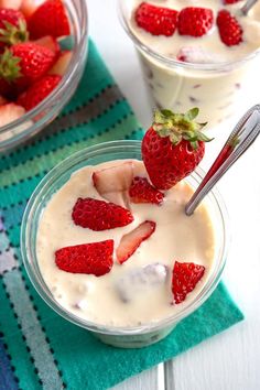 two glasses filled with yogurt and strawberries on top of a blue towel