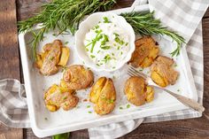 baked potatoes on a serving tray with sour cream and fresh herbs for garnish