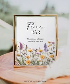 a flower bar sign sitting on top of a wooden table