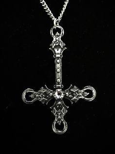 The Blasphemet is an artistic piece handcrafted in fine pewter, featuring a striking inverted cross design adorned with four demon heads and a Swarovski crystal in the color of your choice. This pendant comes with an 18-inch stainless steel chain, designed to be both hypoallergenic and durable. Made from high-quality materials, including 98% tin. The inverted cross measures 6.5 cm and each necklace is accompanied by a certificate of authenticity, confirming that it has been entirely handcrafted Gothic Stainless Steel Cross Pendant Jewelry, Medieval Silver Cross Pendant Jewelry, Medieval Silver Cross Jewelry, Gothic Cross Pendant With Oxidized Finish, Gothic Silver Metal Cross Necklace, Gothic Oxidized Cross Pendant Jewelry, Gunmetal Cross Metal Jewelry, Gothic Silver Pendant Cross Necklace, Silver Gothic Crucifix Jewelry