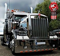 a large semi truck parked in a parking lot next to other trucks and trees on a cloudy day