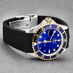 Stainless steel case with a black rubber strap. Uni-directional rotating gold-tone bezel with an inlaid blue ring. Blue dial with gold-tone hands and dot hour markers. Minute markers around the outer rim. Dial Type: Analog. Luminescent hands and markers. Date display at the 3 o'clock position. Automatic movement. Scratch resistant sapphire crystal. Solid case back. Round case shape. Case size: 42 mm. Case thickness: 13 mm. Band width: 22 mm. Band length: 8 inches. Fold over clasp with a safety r Blue Ring, Ring Blue, 3 O Clock, Swiss Made, Blue Rings, O Clock, Black Rubber, Men's Watch, Luxury Watch