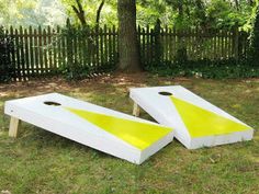 two white and yellow cornhole boards sitting in the grass