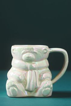 a white ceramic mug with a bear on the front and bottom, sitting upright against a green background