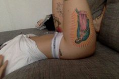 a woman laying on top of a couch with tattoos on her stomach and arm behind her back