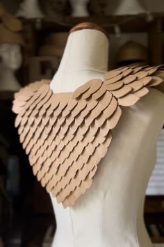 a white mannequin with brown leather wings on it's chest and back