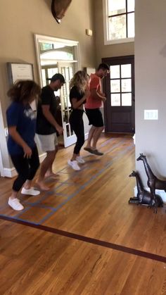 a group of people standing in a room on top of a hard wood floor next to an exercise bike