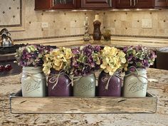 four mason jars with flowers in them sitting on a kitchen counter