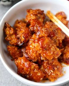 a white bowl filled with meat and chopsticks