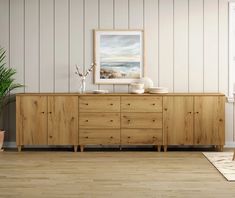 an empty room with a large wooden dresser and potted plant on the sideboard