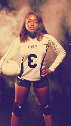 a woman is posing for a photo with her hands on her hips while holding a soccer ball