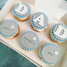 four decorated cupcakes in a box with the letters dad and father's day written on them