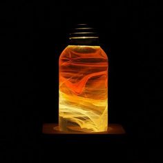 a jar that has some kind of liquid inside of it on a wooden stand in the dark