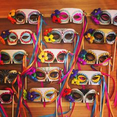 many masks are lined up on a table with ribbons around them and some have flowers in them