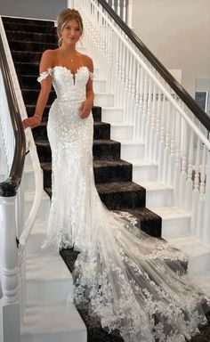 a woman in a white wedding dress standing on stairs with her hand on her hip