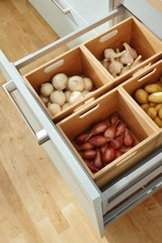 an open drawer in a kitchen filled with different types of potatoes and onions on the counter