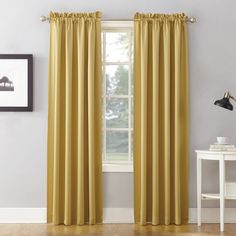 a yellow curtain hanging in front of a window with a white table and chair next to it