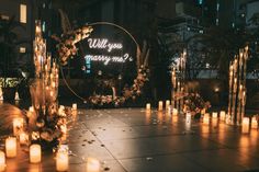 candles are lit on the ground in front of a sign that says will you marry me?