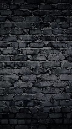 an old brick wall is shown in black and grey colors with some light coming from the top