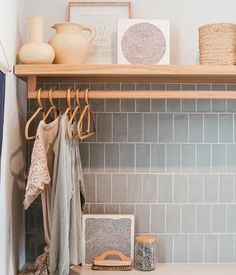 a shelf filled with clothes and other items on top of a white tiled kitchen counter