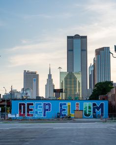 an empty parking lot in front of a large cityscape with the words deep elum painted on it