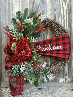 a red and black wreath with the word welcome on it sitting in front of a wooden fence