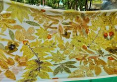 a cloth covered with yellow leaves on a green tablecloth in front of some trees