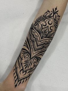 a black and white tattoo design on the left arm, with an intricate pattern in the middle