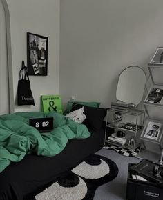 a bedroom with black and green bedding, pictures on the wall and other accessories