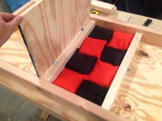 someone is opening up a wooden box with red and black items in it on the table