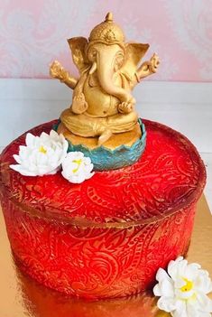 an elephant statue sitting on top of a red box with white flowers in front of it