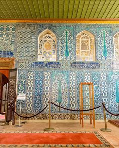 an ornately decorated room with blue and white tiles on the walls, windows and rugs