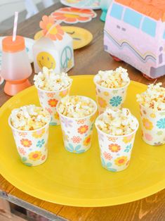 small cups filled with popcorn sitting on top of a yellow plate next to paper napkins