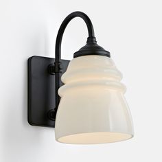 a black and white light mounted on a wall next to a lamp fixture with a white glass shade