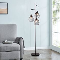 a living room with a gray chair and two lamps on the floor next to it