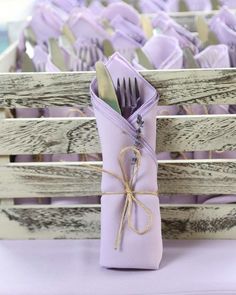 a purple napkin wrapped in twine and tied to a wooden box with silverware