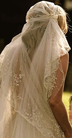 the back of a bride's wedding dress, with veil draped over her head