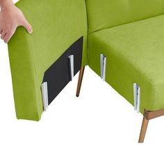 a person is holding the arm rest of a green couch with two separate sections on each side