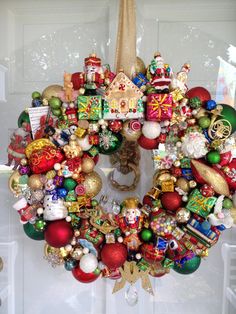 a christmas wreath hanging on the front door with ornaments around it and an ornament