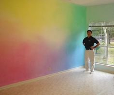 a man standing in front of a rainbow colored wall