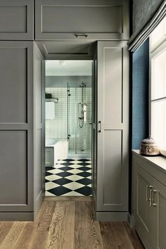 a bathroom with gray cabinets and black and white checkered flooring on the walls