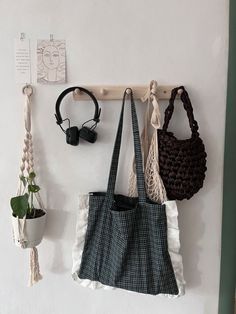 three purses are hanging on the wall next to some hooks and plant hangers