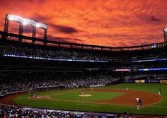 a baseball game is being played in a stadium at sunset with the sun going down