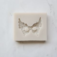 a soap bar with wings on it sitting on a marble counter top next to two white buttons