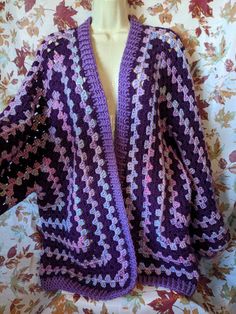 a purple crocheted shawl sitting on top of a mannequin