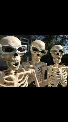 three skeletons wearing sunglasses and standing in front of a house