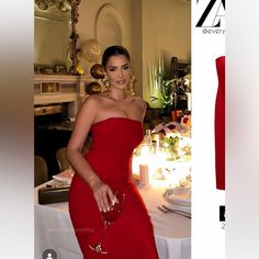 a woman in a red dress standing next to a table