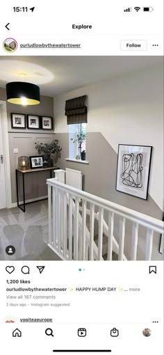 an image of a room with pictures on the wall and stairs to the second floor