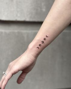 a person's hand with a small tattoo on it that has five phases of the moon