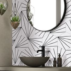 a bathroom sink with a circular mirror above it and plants in vases on the wall